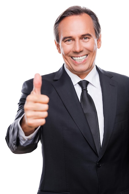 Great job! Happy mature man in formalwear showing his thumb up while standing against white background