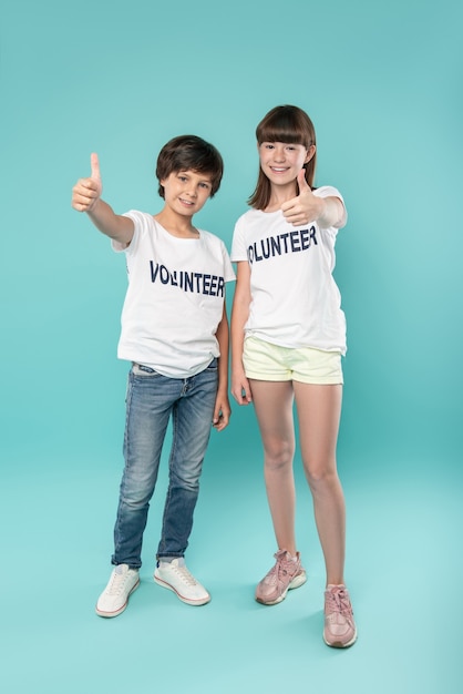 Great mood. Inspired dark-haired girl and boy smiling and showing thumbs up