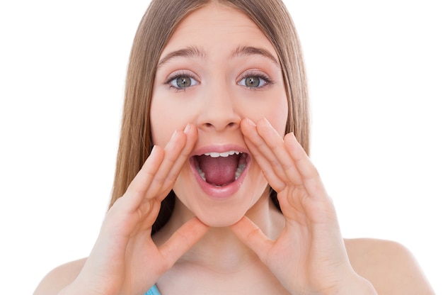 Great news! Cheerful teenage girl shouting and holding hands near mouth while isolated on white