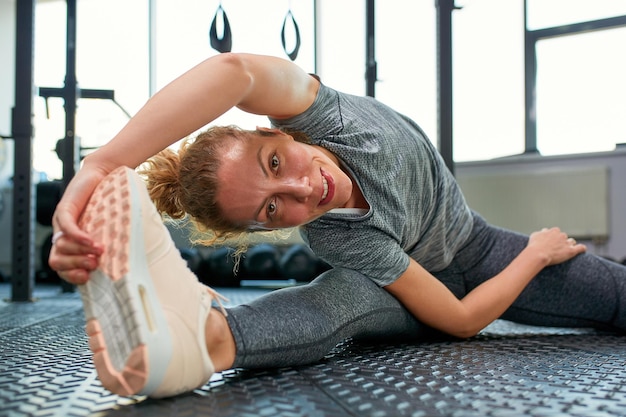 Great progress Young beautiful woman in sportswear doing stretching in front of window at gym