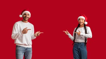 Great promo happy arab spouses in santa hats pointing at copy space