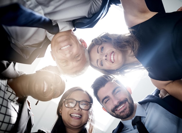 Great things happen when we put our heads together Low angle portrait of a team of happy colleagues putting their heads together in a huddle in the office