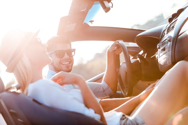 The greatest day for the road trip. Happy young couple smiling while sitting inside of their convertible