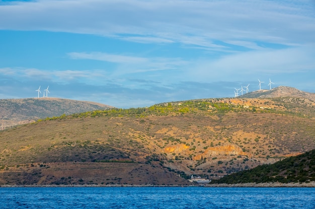 ギリシャ。コリントス湾。丘の上の風力発電所のある丘陵地帯。ボートからの眺め