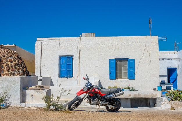 ギリシャ。サントリーニ島のイアの町。地元の家の前にある赤いバイク