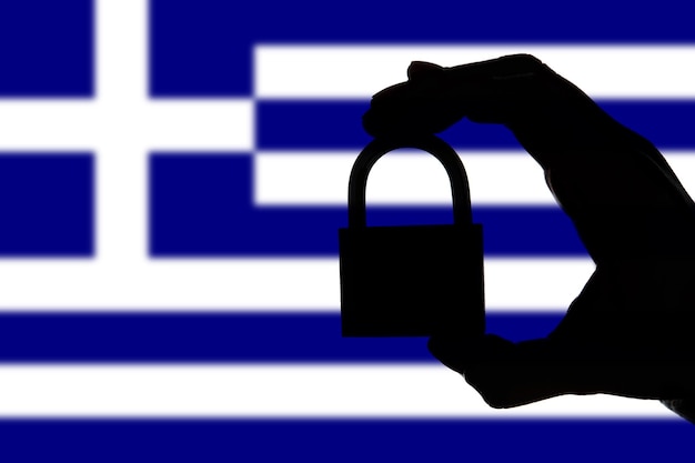 Greece security Silhouette of hand holding a padlock over national flag