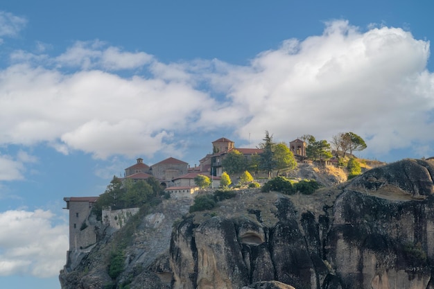 Greece Sunny summer day in Kalambaka Large rock monastery with red roofs above the clouds