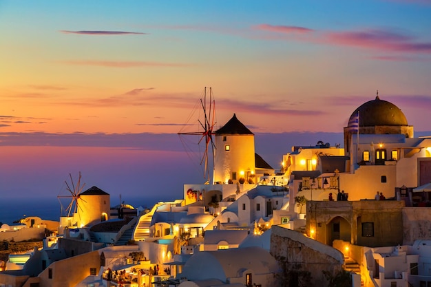 Greece vacation background Famous iconic Oia village with traditional white houses and windmills during colorful sunset Santorini island Greece