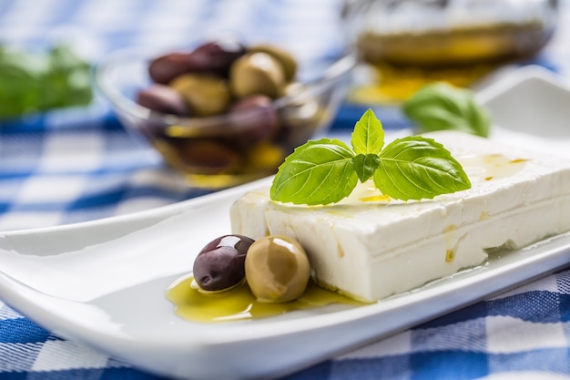 Greek cheese feta with olive oil olives and basil leaves.