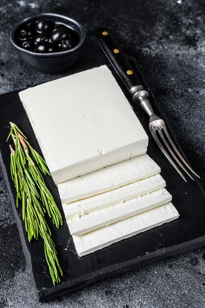 Greek cheese feta with rosemary and olives. Black background. Top view.