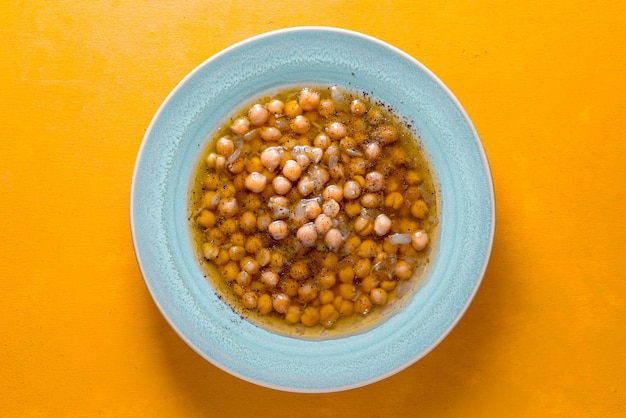 Greek chickpea soup in the white plate on the yellow background top view horizontal