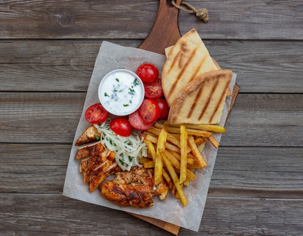 Greek dish gyros with chicken, french fries, tomatoes, onions and pita. Greek cuisine.