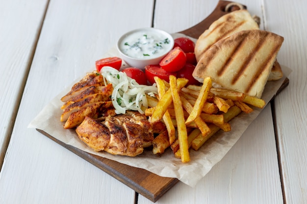 Greek dish gyros with chicken, french fries, tomatoes, onions and pita. Greek cuisine.