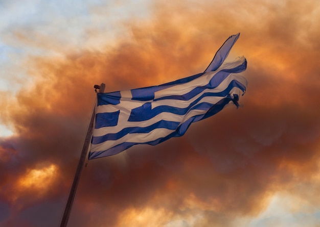 Greek flag on the background of smoke from fires in Greece