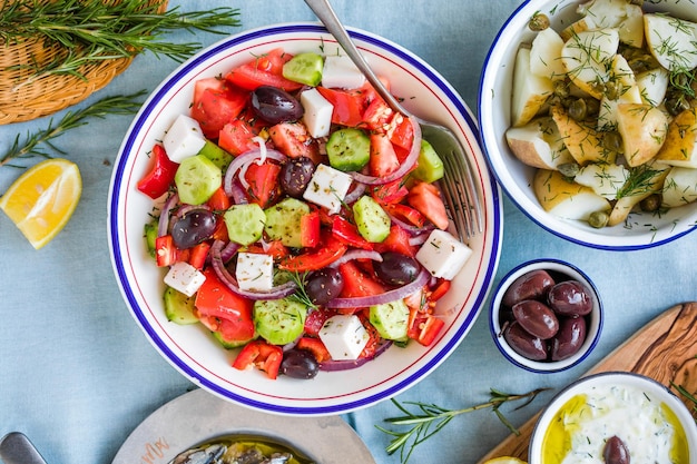 Greek food table scene top view Variety of items including greece salad cucumber dip Tzatziki Anchovy fillets lemon potatoes