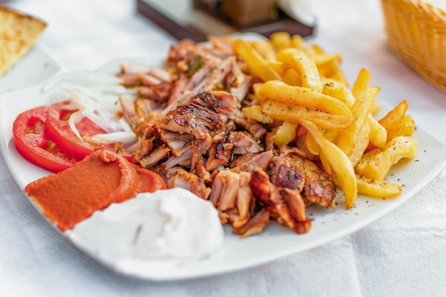 Greek gyros on a plate with French fries and vegetables