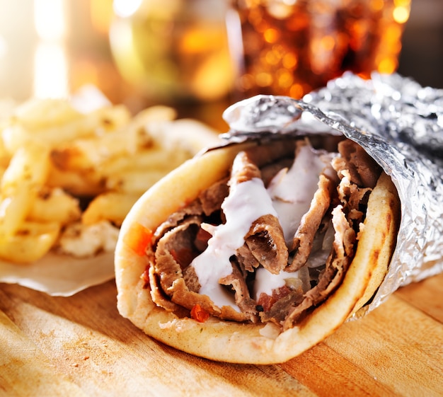 Greek gyros with fries on a wooden board