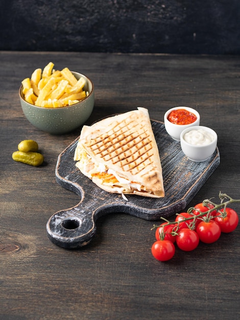 Greek gyros wrapped in pita breads with vegetables and sauce Dark wooden background Vertical Copy space