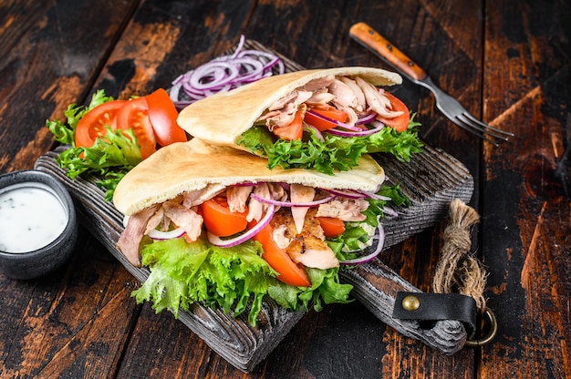 Greek gyros wrapped in pita breads with vegetables and sauce.