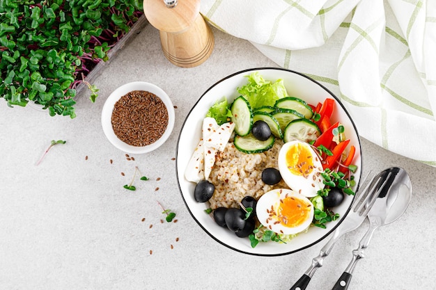 Greek inspired savory oatmeal with fresh cucumber bell pepper olives lettuce feta cheese radish sprouts and softboiled egg for healthy breakfast top view