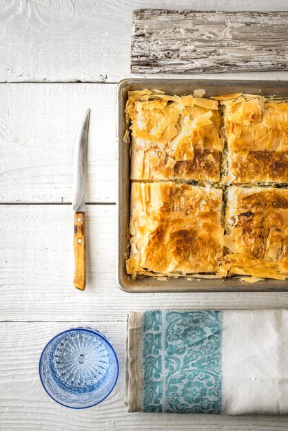 Photo greek pie spanakopita in the metal pan with table ware vertical