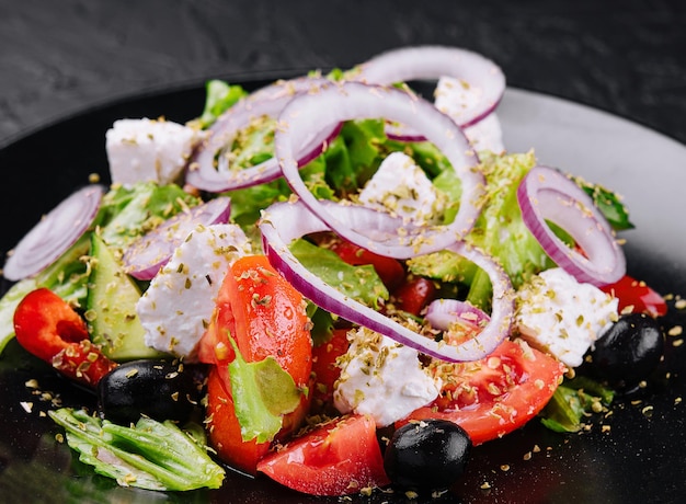 Greek salad in black bowl on stone