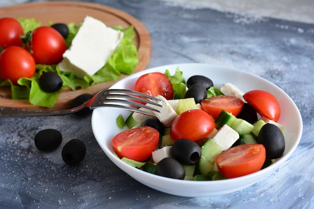 greek salad in bowl with fork on the concrete background