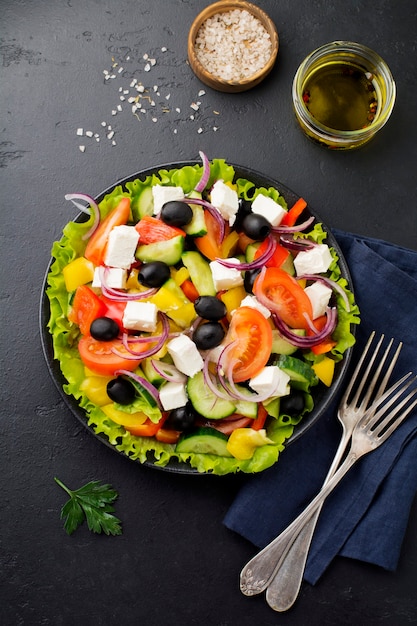 Greek salad in ceramic plate on  black concrete