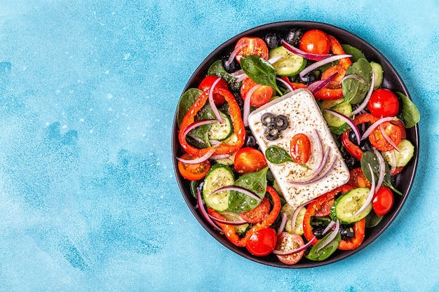 Greek salad of fresh cucumber, tomato, sweet pepper, spinach, red onion, feta cheese and olives