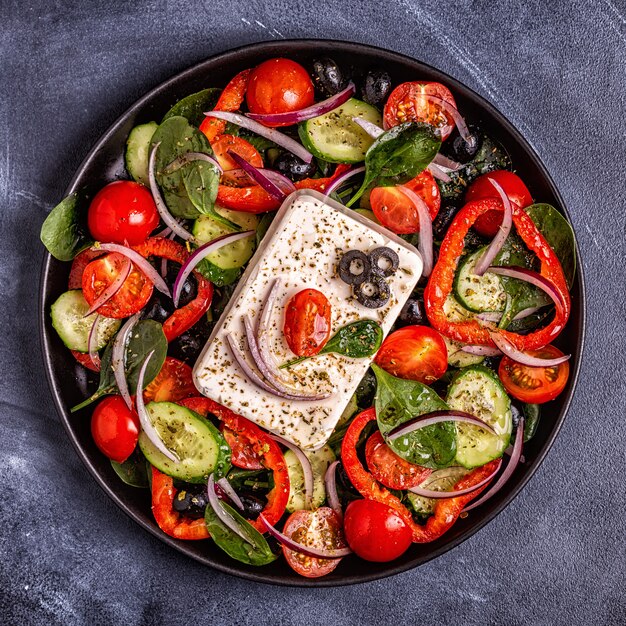 Greek salad of fresh cucumber, tomato, sweet pepper, spinach, red onion, feta cheese and olives