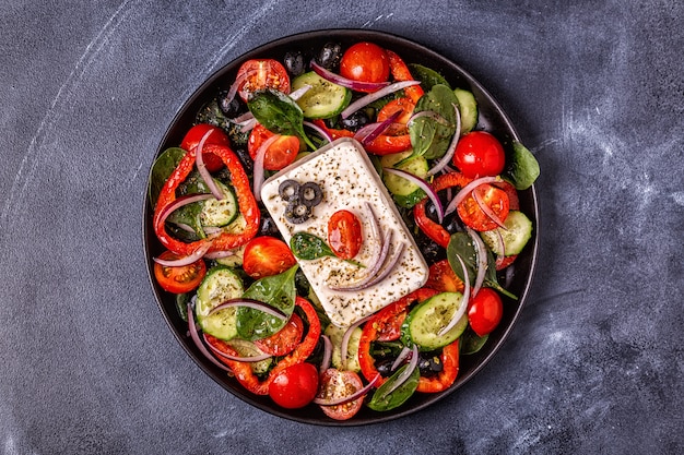 Greek salad of fresh cucumber, tomato, sweet pepper, spinach, red onion, feta cheese and olives