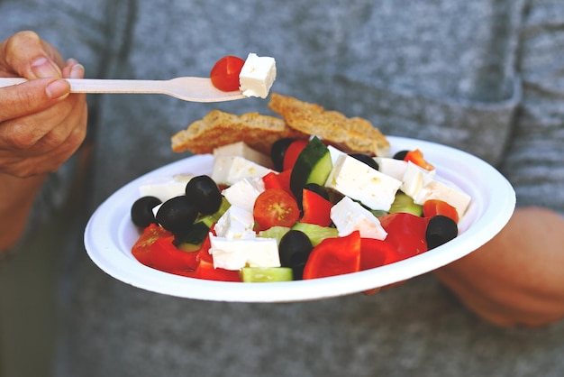 Greek salad on a plate in female hands Healthy food concept Keto salad