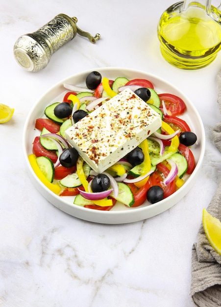 Greek salad in a plate on a grey marble background. Restaurant dish. Vegetable salad with olive oil