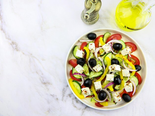 Greek salad in a plate on a grey marble background. Restaurant dish. Vegetable salad with olive oil