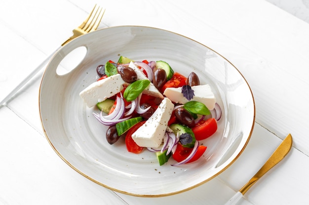 Greek salad in plate on white wooden background