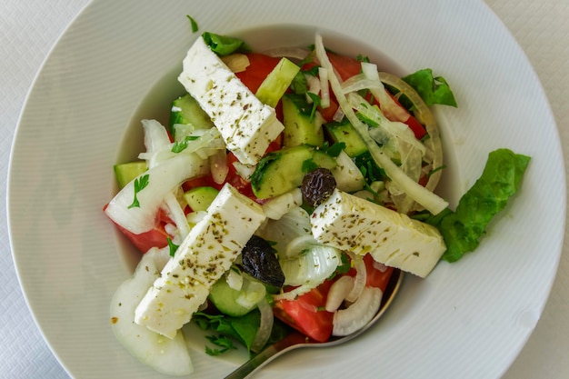 Greek salad served with olives white cheese oregano chopped tomatoes cucumber and green vegetables