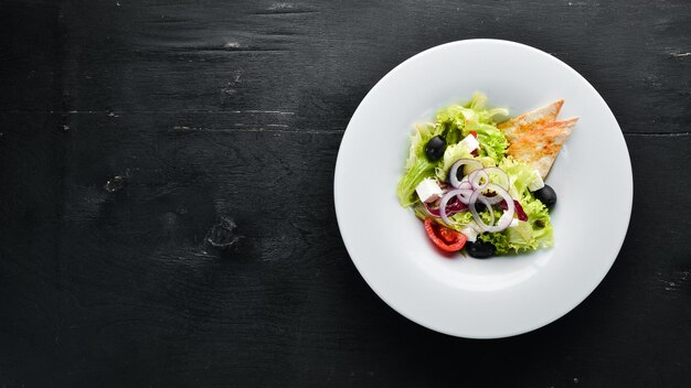 Foto insalata greca insalata di verdure con feta olive e pomodorini nel piatto vista dall'alto spazio libero per il testo stile rustico