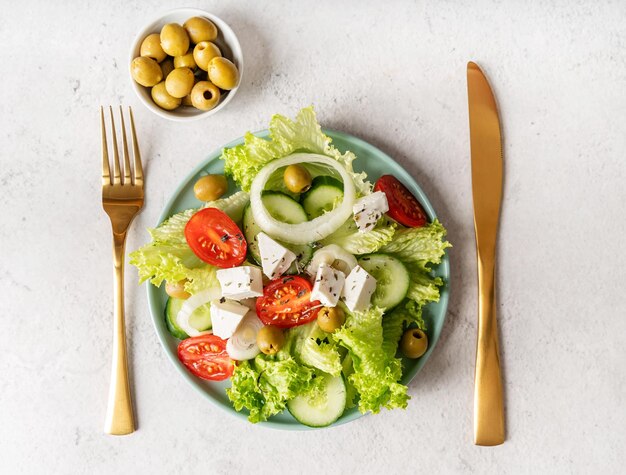 Greek salad with feta cheese fresh vegetables and olives on white rustic background top view