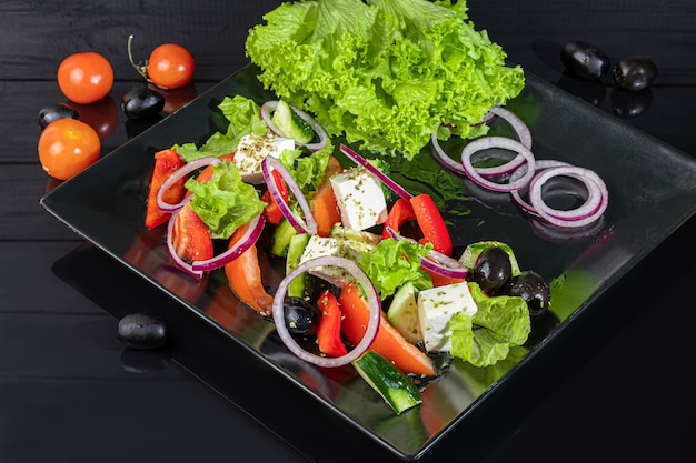 Greek salad with feta tomatoes olives and lettuce On a dark background copy space