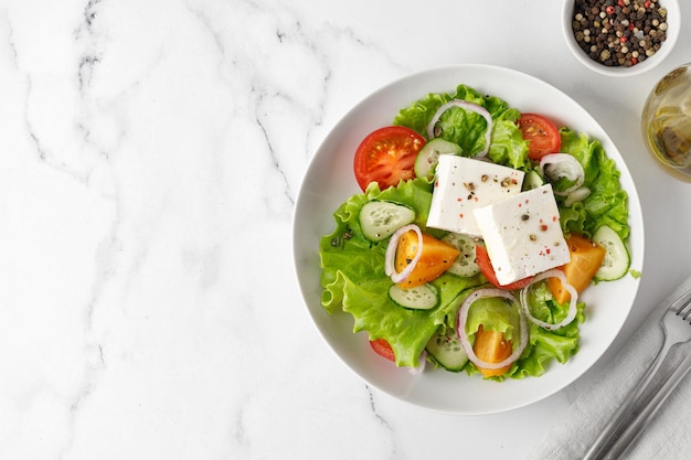 Greek salad with fresh vegetables feta cheese and tomatoes Healthy food Top view marble Copy space