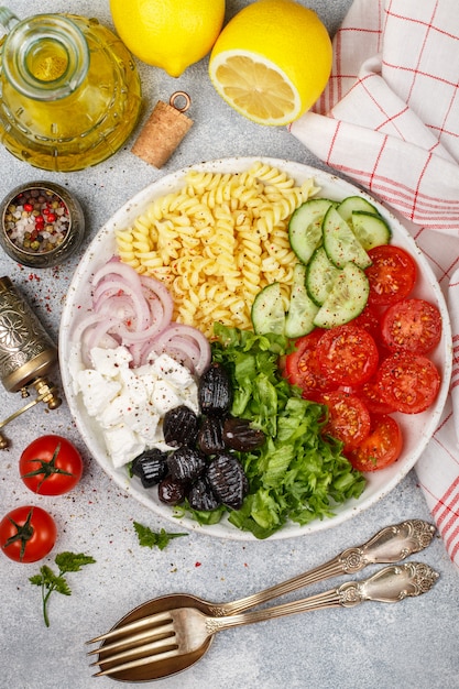 Greek salad with fusilli paste, lettuce, tomatoes, cucumber, feta cheese, red onions and black olives