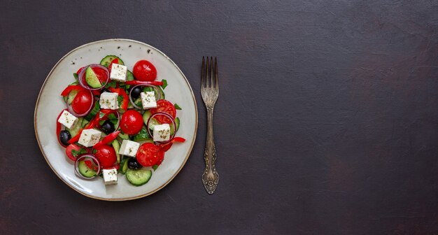 Greek salad with tomatoes, cucumbers, cheese, onions, peppers and olives