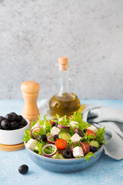 Greek salad with tomatoes, cucumbers, olives and feta cheese in a plate on a concrete background, typical Greek cuisine, copy space