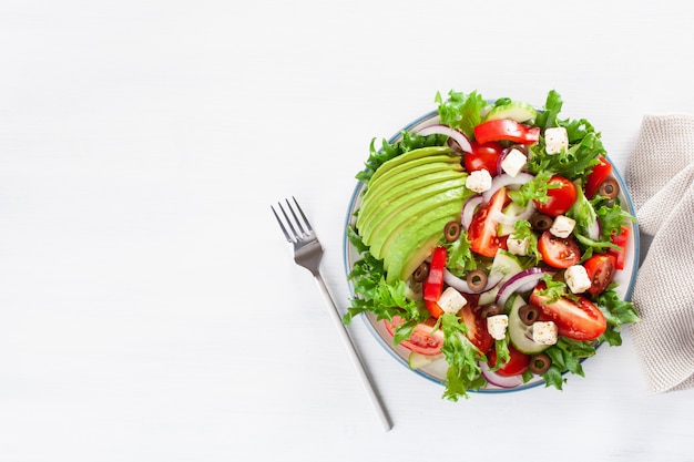 Greek style avocado tomato salad with feta cheese, olives, cucumber, onion, lettuce