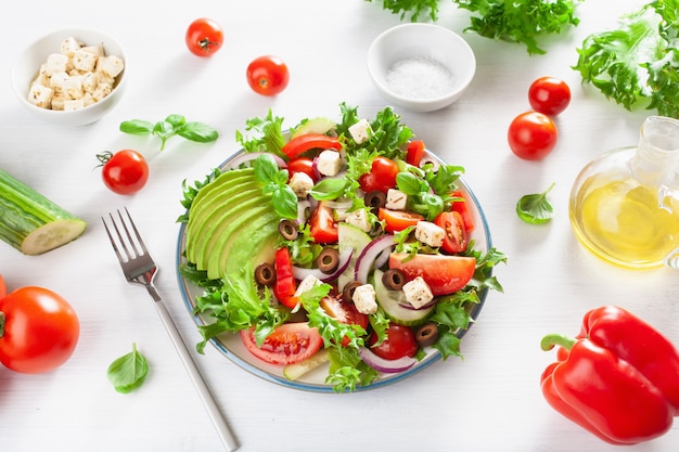 Greek style avocado tomato salad with feta cheese, olives, cucumber, onion, lettuce