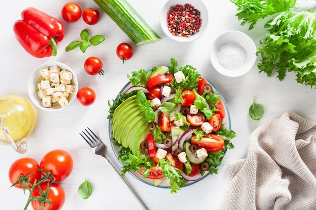 Greek style avocado tomato salad with feta cheese, olives, cucumber, onion, lettuce