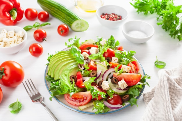 Greek style avocado tomato salad with feta cheese, olives, cucumber, onion, lettuce