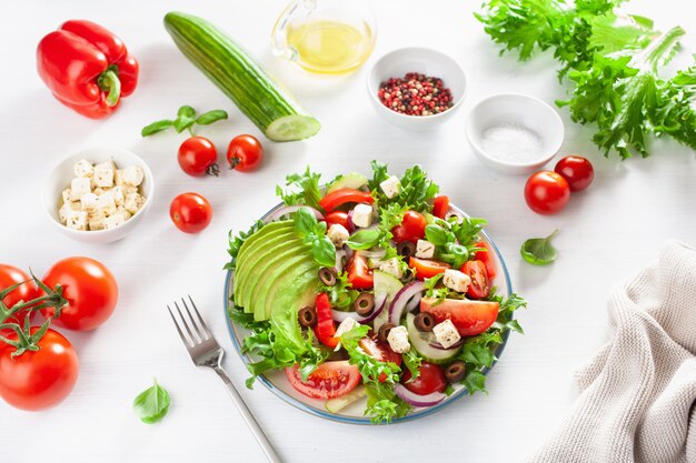 Photo greek style avocado tomato salad with feta cheese, olives, cucumber, onion, lettuce