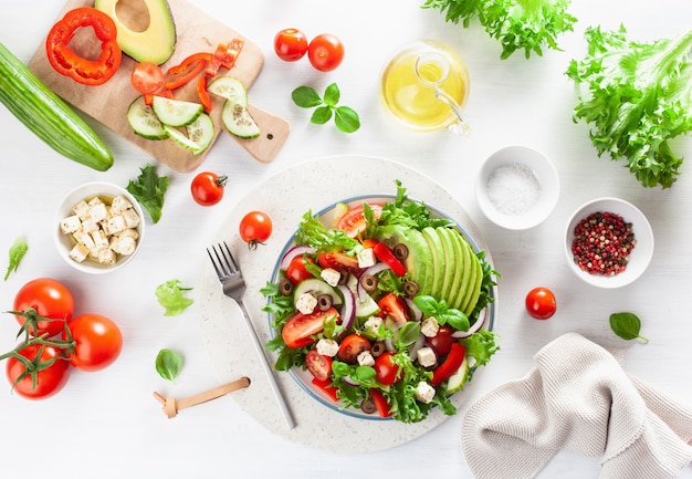 Greek style avocado tomato salad with feta cheese, olives, cucumber, onion, lettuce