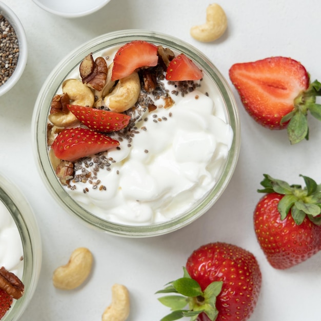 Greek yogurt nuts and strawberries in a glass jars on a white table top view